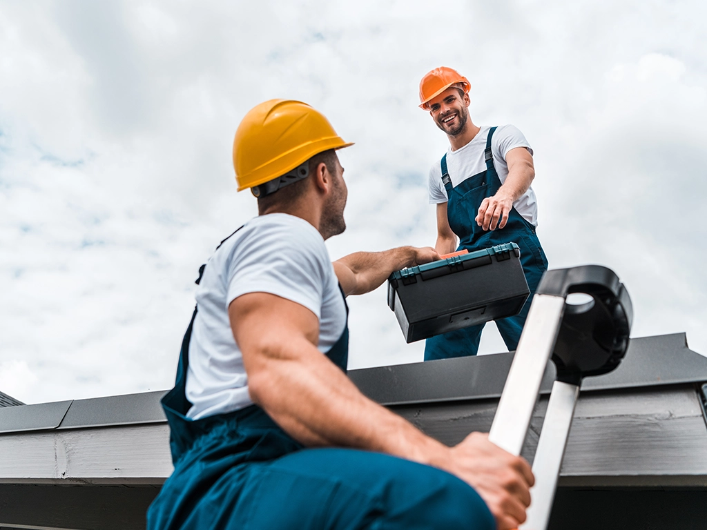 Montage-Team bei Installation einer Solarthermieanlage – Facharbeiter von Akotec arbeiten am Dach mit Werkzeugkoffer und Schutzhelmen.