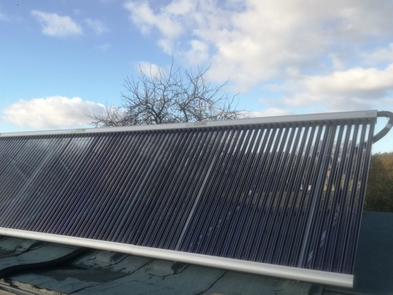 Vakuumröhrenkollektor zur Solarthermie auf einem Flachdach installiert, vor einem bewölkten Himmel. Effiziente Nutzung von Sonnenenergie zur Warmwasserbereitung und Heizungsunterstützung.