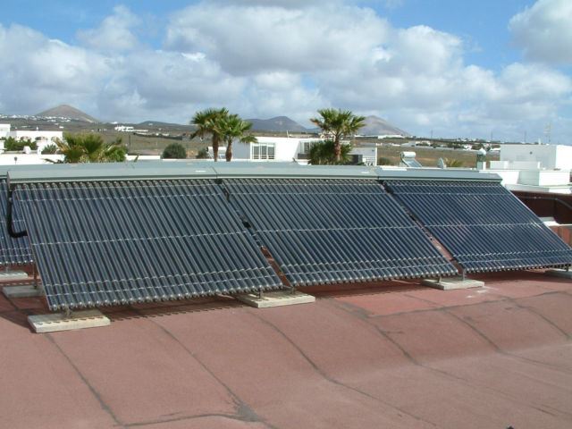 Das Bild zeigt eine moderne Solarthermie-Anlage mit Vakuumröhrenkollektoren auf einem Flachdach. Diese hocheffiziente Technologie nutzt Sonnenenergie zur nachhaltigen Warmwasserbereitung und Heizungsunterstützung.